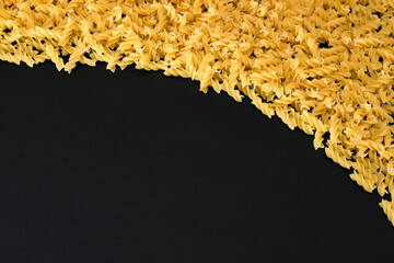 Uncooked Fusilli Pasta with Copy Space on Black Background. Raw and Dry Macaroni. Fat and Unhealthy...