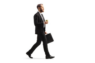 Full length profile shot of a businessman walking with a takeaway coffee cup and a briefcase - obrazy, fototapety, plakaty