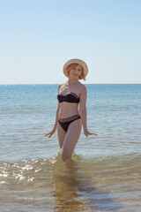 Portrait of a mature woman in a swimsuit and a hat at the sea. Travel and vacation at sea