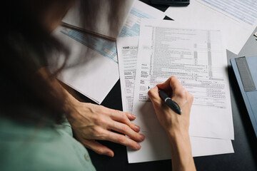 Woman filling US tax form 1040. tax form us business income office hand fill concept