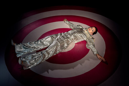 High angle 3/4 portrait of a woman laying on large hand painted Bulls-eye target