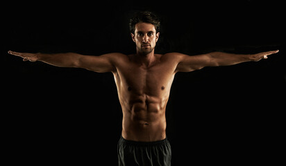 Fototapeta na wymiar Perfect form. Handsome topless man raising his arms to his side - Isolated on black.