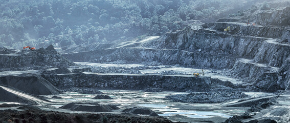 Mining machines and piles of crushed stone in diabase quarry (Cyprus), industrial landscape