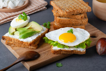 Sandwiches with curd cheese, fried egg, avocado and herbs