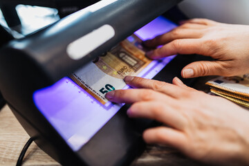 A female worker in an exchange office checks the correctness of banknotes through the device.