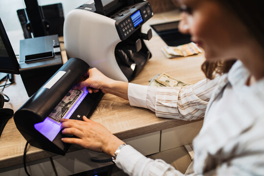 A female worker in an exchange office checks the correctness of banknotes through the device.
