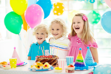 Fototapeta premium Kids birthday party. Child blowing out cake candle