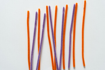 orange and violet pipe cleaners on a light background