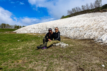 A girl with a man near a glacier on the Lago-Naki plateau. Snow in Adygea. Russia. 2021.