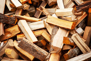 Background in the form of firewood chopped for heating the house, stacked randomly. Closeup.