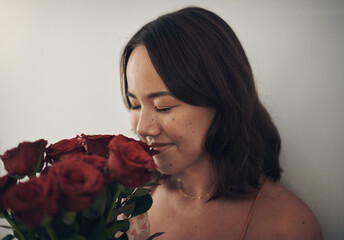 I dont have to wake up to smell the roses. Shot of a young woman smelling roses at home.