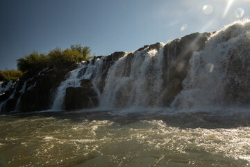 The Mocona waterfalls at sunset. Beautiful view of the Moconá falls seen from a ship navigating the river, with a beautiful lens flare, at dusk.