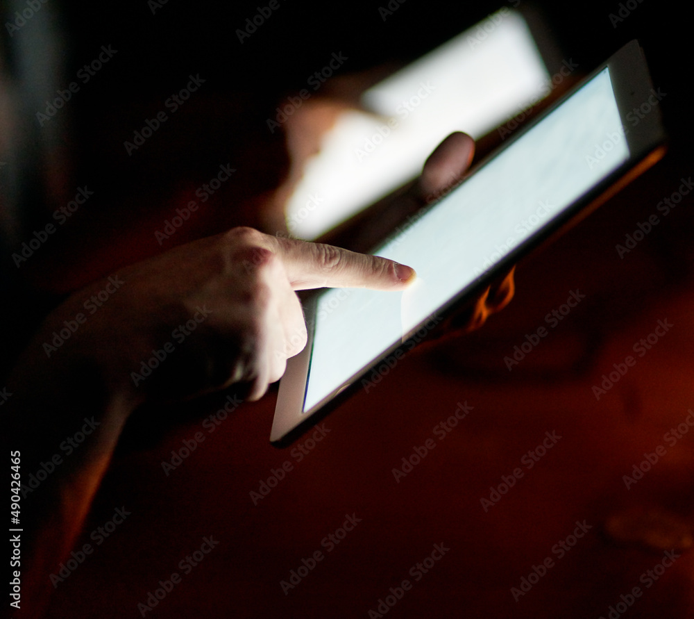 Poster connected in the late hours. closeup shot of two people using digital tablets in the dark.