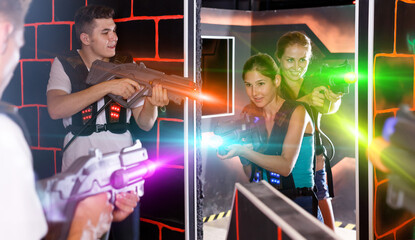 Fototapeta na wymiar Lucky Laser tag players young mens and womens playing in teams in dark laser tag station