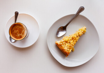 Slice of appetizing crunchy Dutch apple pie with shortcrust pastry, flavorful fruit filling and streusel crumb topping served with glass of sweet hot chocolate