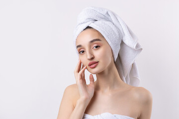 Beautiful girl with thick eyebrows and perfect skin at white background, towel on head, beauty photo.