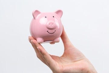 3d pink piggy bank in the beautiful hands of a girl..Close-up photo on a white background.