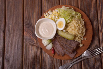 Fototapeta na wymiar Salad ingredients. Bulgur, beef, sauce on a round wooden board. Empty place