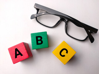 Top view glasses and colored block with word ABC on white background.