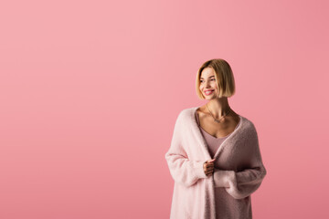 pleased young woman in cardigan isolated on pink.