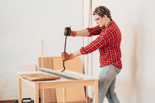 Laborer girl with crowbar in her hands breaks boards.