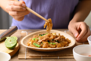 Thai food (Pad See Ew), Stir fried rice noodles with soy sauce, egg, kale and pork eating by use chopsticks