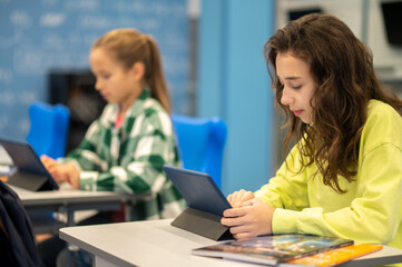 Girls sitting and looking at tablets