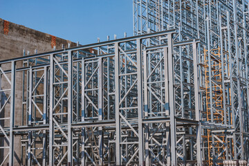 Structure of a new steel frame of a building on an industrial construction site. Against the background of the sky.