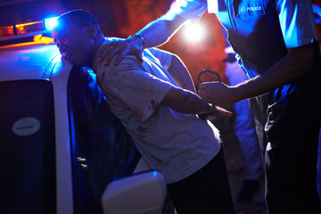 To serve and protect. Shot of a police officer handcuffing a suspect against his patrol car. © Yuri A/peopleimages.com