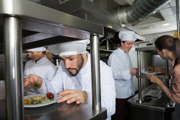 Chef of restaurant with team of cooks busy to preparing food for they client