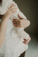 mom is holding a newborn baby in her arms. baby feet. pastel neutral clothes. mom's care, family values. selective focus