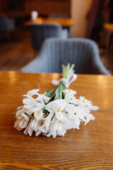 white bouquet of fresh white iris flowers on  wooden table served in vintage room. Spring decor in vintage style. vertical content, selective focus
