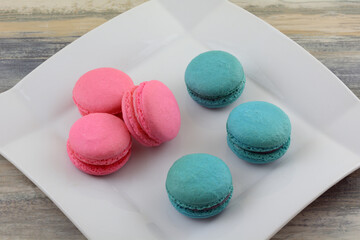 Raspberry and blueberry macarons snacks on white dessert plate on table
