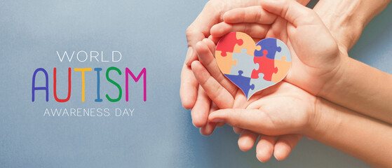 Adult and chiild hands holding jigsaw puzzle heart shape, Autism awareness, Autism spectrum family support concept, World Autism Awareness Day