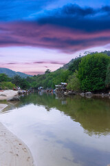 Colourful sky at sunset and lovely lush green mountains in a fishing village Patong phuket thailand. Long-tail boats and fishing timber huts long tail boats