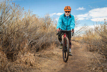 senior male cyclist is riding a gravel bike on a single track trail in winter or fall scenery - Arapaho Bend Natural Area in Fort Collins, Colorado