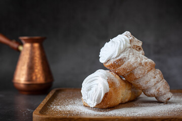 Puff pastry horns filled with white cream and powdered sugar