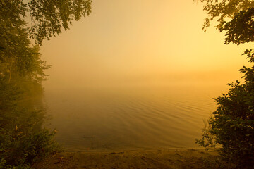 Warm summer sunrise and mist on Spectacle Pond in Vermont.