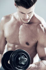 Fototapeta na wymiar Pumping iron. A muscular male doings reps with a weight.