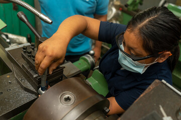 Latin young woman working on an industrial lathe as a symbol of female empowerment