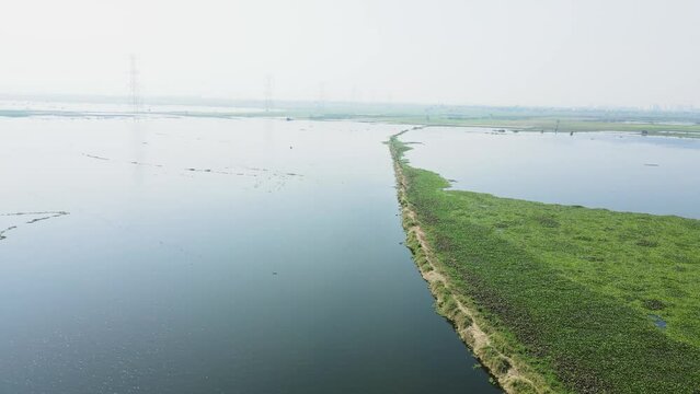 Aerial drone shot of agricultural lands covered in water with high voltage electrical pylon.