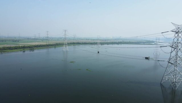 Aerial drone shot of the agricultural land covered in water due to heavy rain, high voltage electric towers in the agricultural fields.