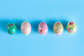 Colorful, painted for Easter, chicken eggs lie in a row on a blue background