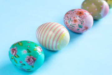 Colorful, painted for Easter, chicken eggs lie sub-diagonally on a blue background