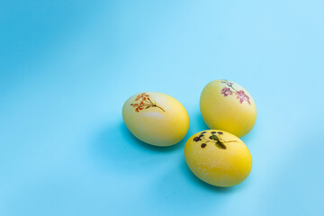 Yellow with a plant pattern of eggs lie on a bright blue background. Painted eggs for Easter