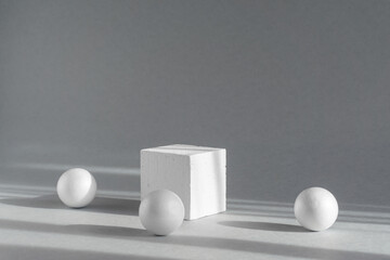 Geometric white square podium pedestal surrounded by spheres. Abstract 3d composition on gray...