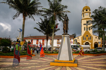 Bolivar Square Salento with statue and church Our Lady of Carmen with dark clouds in background, Cocora Valley, Columbia