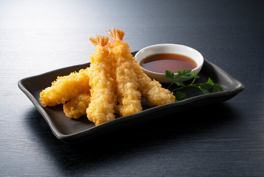 Shrimp tempura on a plate placed against a black background.