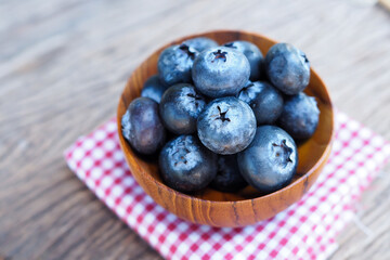 Blueberries in wooden bowl on old wood table background