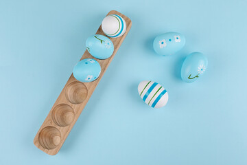 Easter egg on wooden tray on blue background. Flat lay, top view.